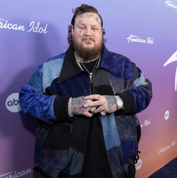 jelly roll crossing his hands while smiling for a photo in front of an american idol backdrop