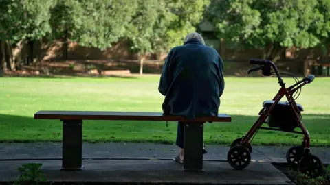 Rear view of Mary, sat on a bench