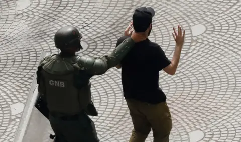 A member of Bolivarian National Guard detains a demonstrator during protests against results of the presidential election