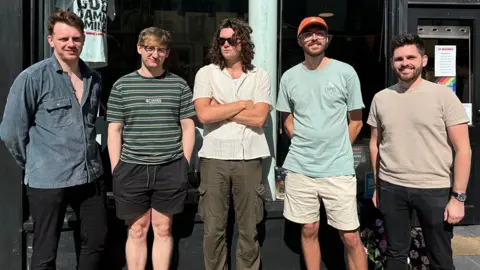 The five members of The Silver Bars band lined up outside a shop