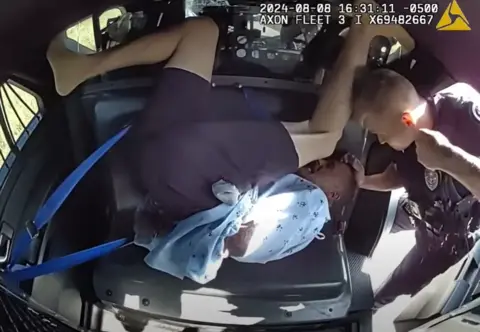 Camera footage shows a police officer punching and elbowing a handcuffed man