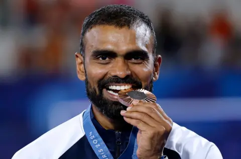 Bronze medallist Sreejesh Parattu Raveendran of India celebrates on the podium.