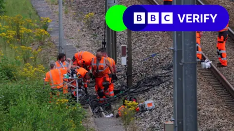 Workers wearing high-visibility clothing at the site where vandals targeted France's train network