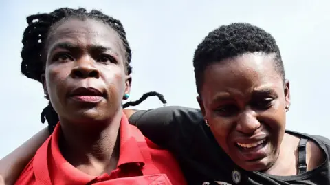 A distraught woman is helped by a member of the Uganda Red Cross Kampala, near Kampala, Uganda August 10, 2024