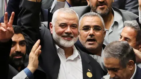 Ismael Haniyeh smiling with arm raised in the middle of crowd of people