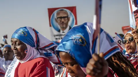 Rwandan Patriotic Front (RPF) supporters wave party flags while dancing to songs in support of Incumbent President of Rwanda and presidential candidate Paul Kagame during a campaign rally in Kigali, on July 13, 2024