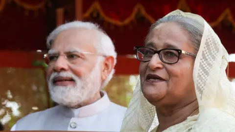 : Bangladesh Prime Minister Sheikh Hasina (R) speaks to the media during the ceremonial reception with Narendra Modi standing nearby at the Rashtrapati Bhavan in New Delh