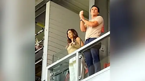 Eva Longoria and McElhenney standing in the executive box