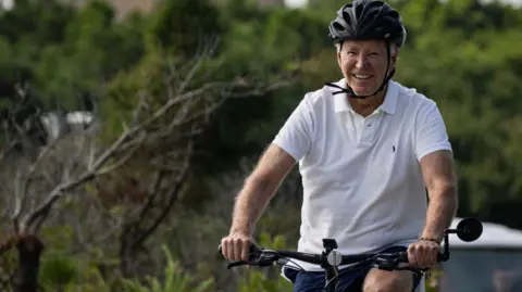 US President Joe Biden rides his bike through Gordons Pond State Park in Rehoboth Beach, Delaware on Sunday