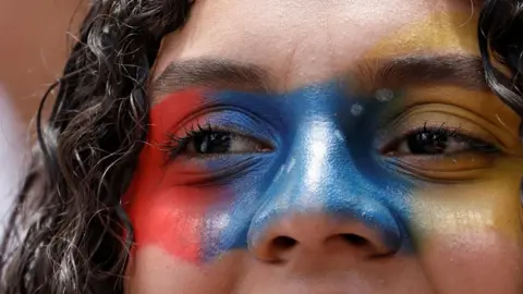 A demonstrator with face paint looks on during a protest against election results