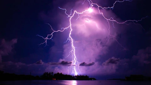 A lightning strike illuminates the sky with a purple hue.