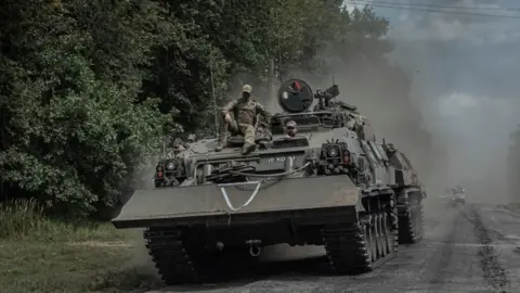 Soldiers ride a tank in the Sumy region close to the Russian border