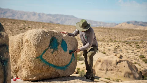 Person spray-painting rock (Credit: Alamy)