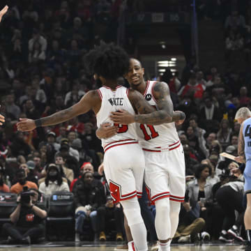 Jan 20, 2024; Chicago, Illinois, USA;  Chicago Bulls forward DeMar DeRozan (11) hugs guard Coby White (0) as center Nikola Vucevic (9) looks on against the Memphis Grizzlies during the second half at the United Center. Mandatory Credit: Matt Marton-USA TODAY Sports