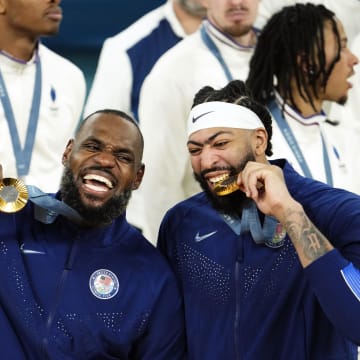 Aug 10, 2024; Paris, France; United States guard LeBron James (6) and centre Anthony Davis (14) celebrate with their gold medals on the podium after defeating France in the men's basketball gold medal game during the Paris 2024 Olympic Summer Games at Accor Arena. Mandatory Credit: Rob Schumacher-USA TODAY Sports