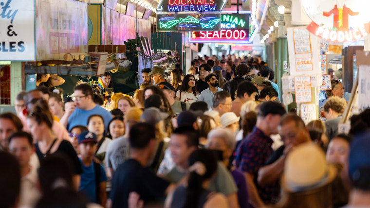 A large crowd of shoppers walking around the market