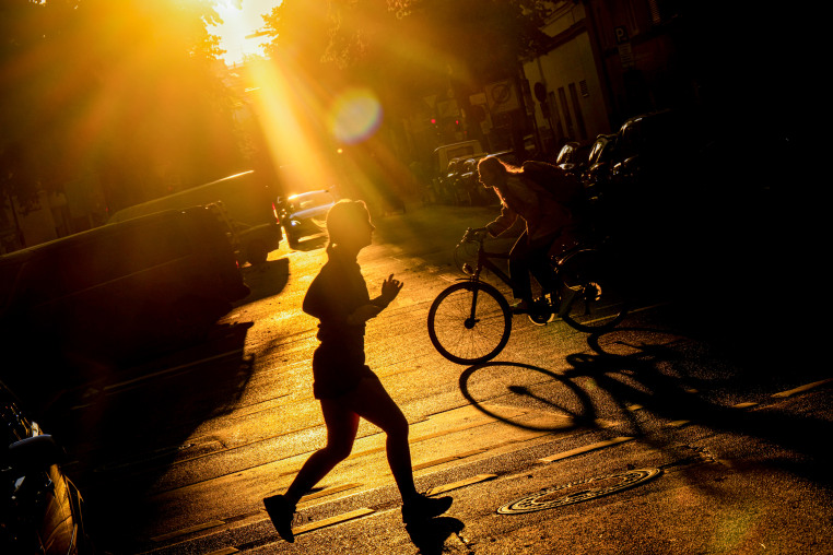 A woman jogs across the shimmering street.