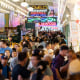 A large crowd of shoppers walking around the market