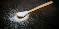 Natural sweetener on a wooden spoon, dark grey marble table with copy space.