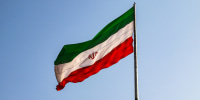 Flag of Iran flies with a clear blue sky in the background