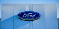 The Ford Motor Company logo is seen atop a dealership.