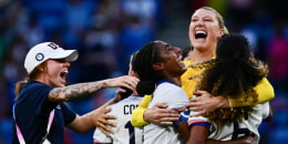 US' goalkeeper Alyssa Naeher is embraced by US' defender Naomi Girma, left, and US' defender Casey Krueger on the soccer field